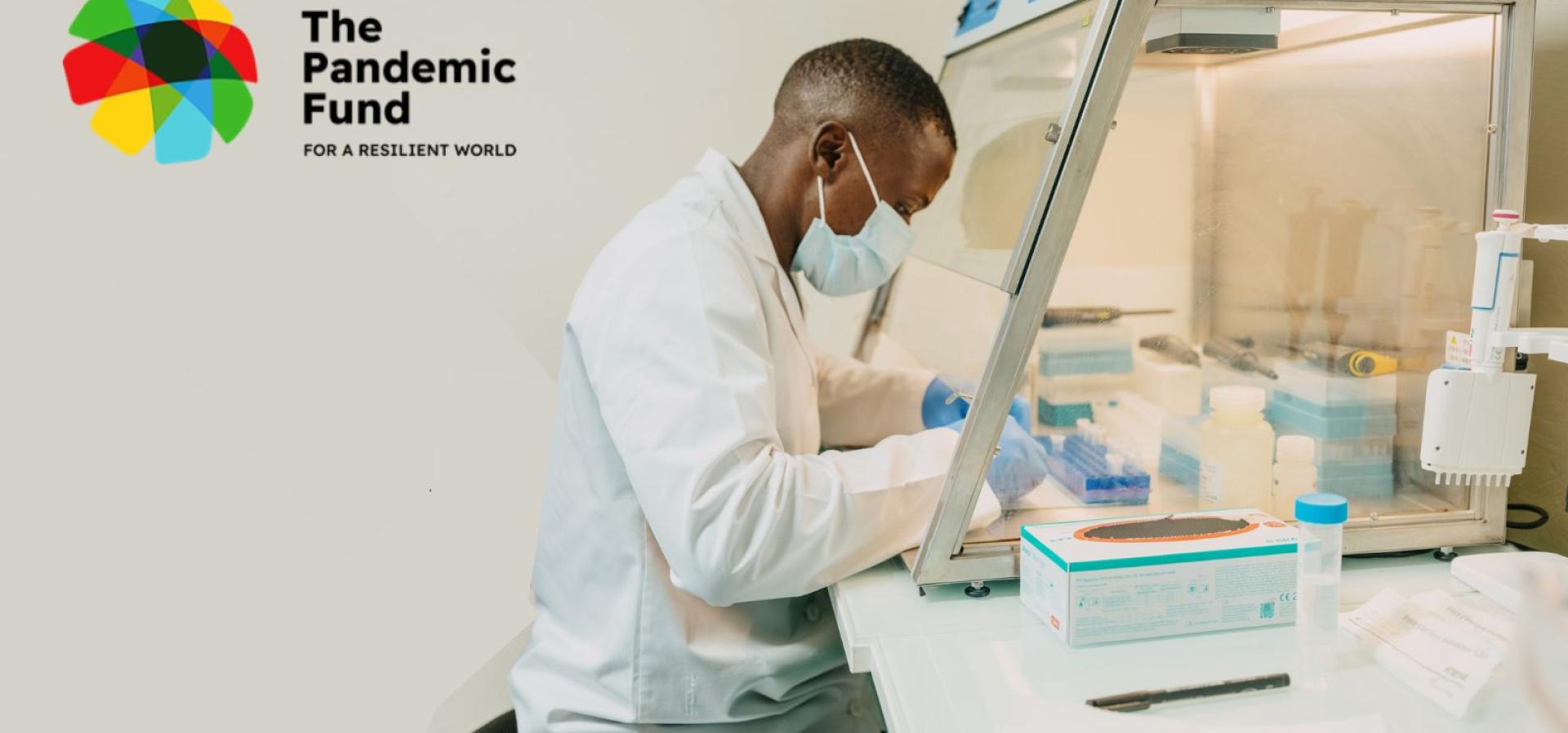 African man in a lab coat, sits in a laboratory looking over research