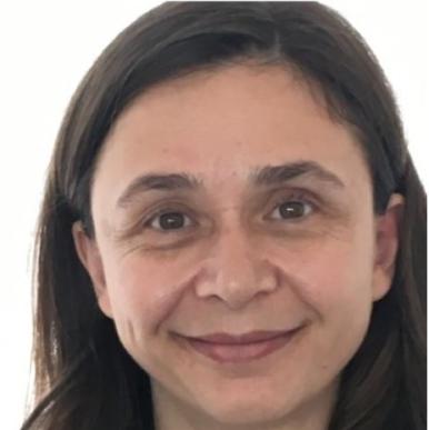 Latina woman with dark brown hair and brown eyes looks into the camera, taken from the chin up