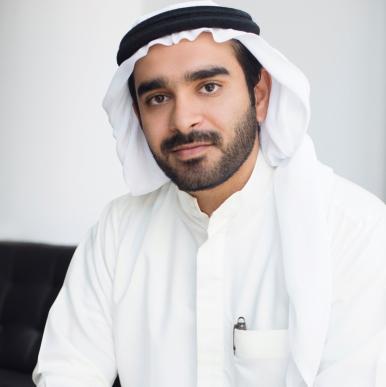 Man wearing a white headscarf and white shirt looks into the camera