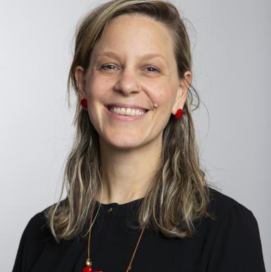 Woman wearing a black shirt and red necklace smile into the camera