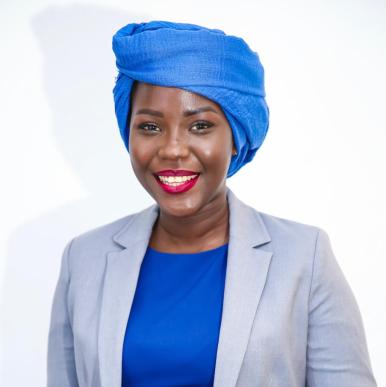 African woman wearing a bright blue head scarf smiles into the camera
