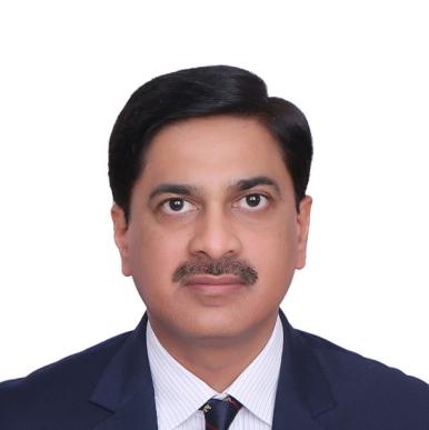 Man wearing a blue suit, with a brown moustache, looks into the camera