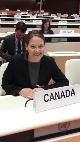 Woman wearing a black sweater sits behind a Canada tent card