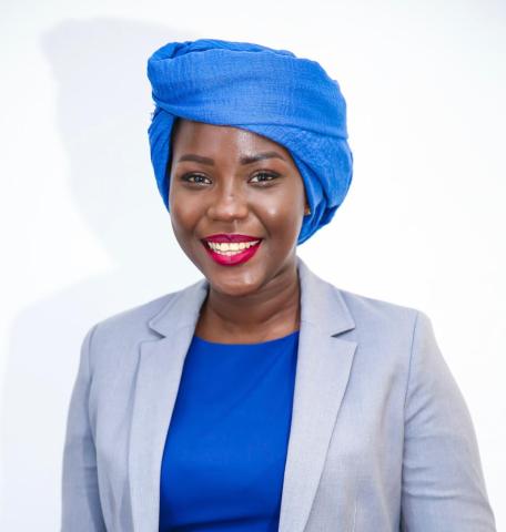 African woman wearing a bright blue head scarf smiles into the camera