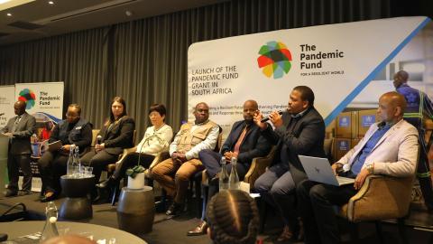 People sit on a panel in front of the Pandemic Fund logo