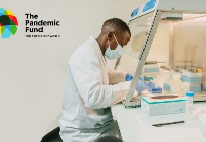 African man in a lab coat, sits in a laboratory looking over research