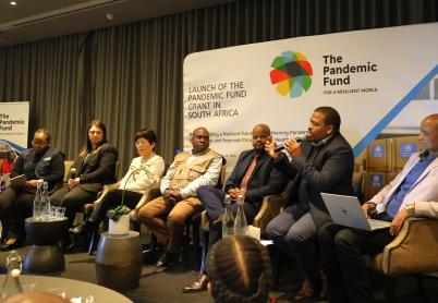 People sit on a panel in front of the Pandemic Fund logo