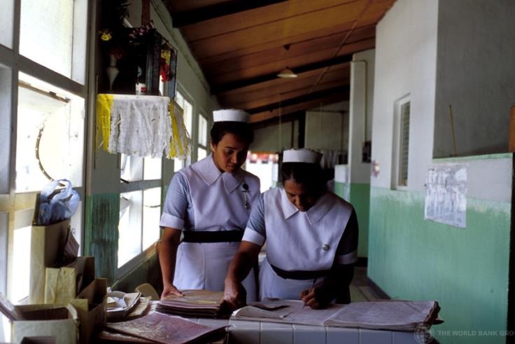Sri Lanka, nurses Two women stand in nurses uniforms, learning over and writing into an administrative book