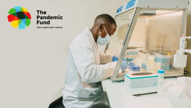 African man in a lab coat, sits in a laboratory looking over research